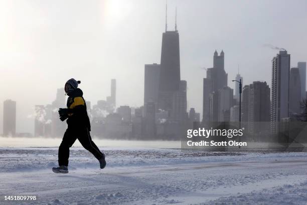 Jogger runs along Lake Michigan at sunrise as temperatures hover about -8 degrees on December 22, 2022 in Chicago, Illinois. Sub-zero temperatures...