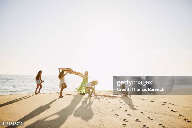 wide shot of friends setting up blanket on beach while on vacation - northern mexico stock pictures, royalty-free photos & images