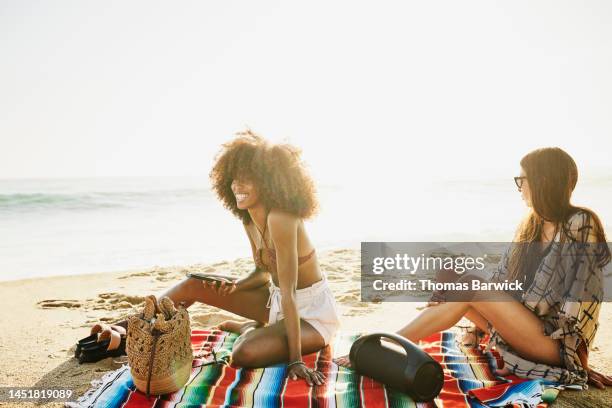 wide shot of smiling woman relaxing with friends on tropical beach - tropical music stock-fotos und bilder