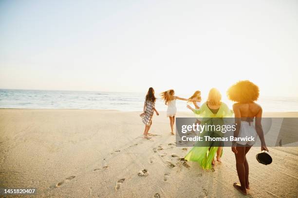 wide shot of female friends dancing while hanging out on tropical beach - carefree beach stock pictures, royalty-free photos & images