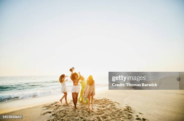 wide shot of female friends dancing on tropical beach at sunset - tropical music stock pictures, royalty-free photos & images