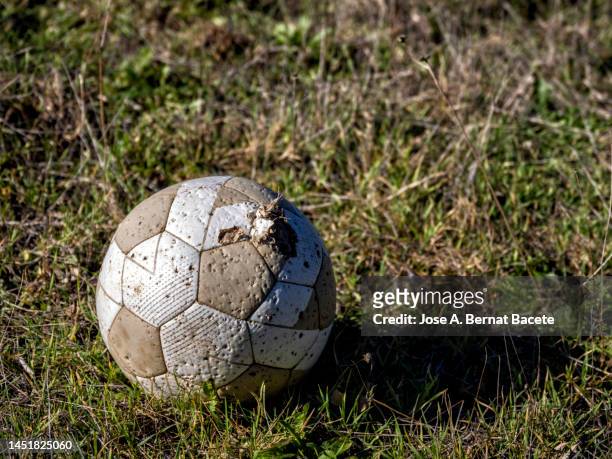 broken and abandoned soccer ball on the grass of the abandoned soccer field. - ballon rebond stock pictures, royalty-free photos & images