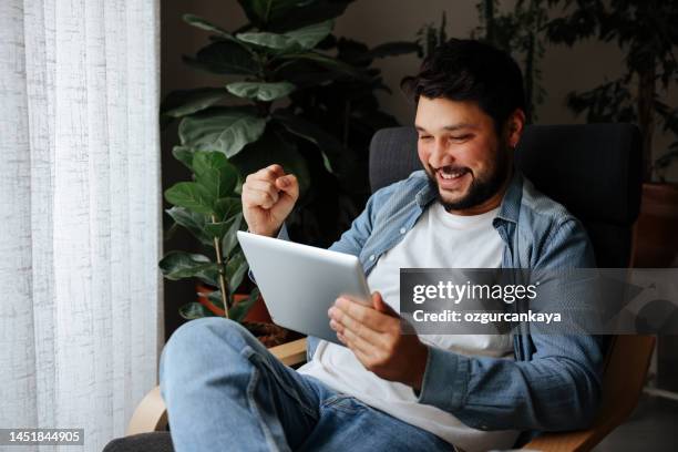 young man looking at digital tablet - internet gambling stock pictures, royalty-free photos & images