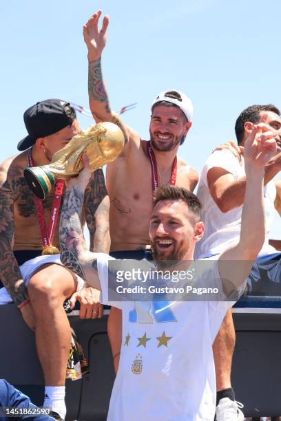 Lionel Messi of Argentina celebrates next to Rodrigo De Paul with the FIFA World Cup Qatar 2022 Winner's Trophy during a victory parade of the...