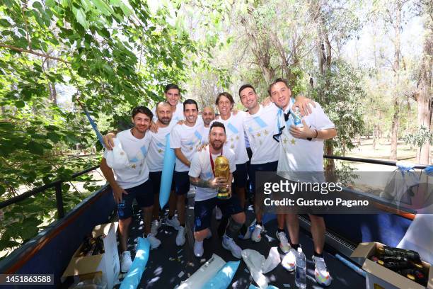 Lionel Messi and the head coach assistants pose with the FIFA World Cup Qatar 2022 Winner's Trophy during a victory parade of the Argentina men's...