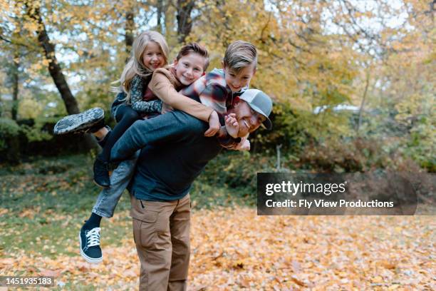 vater mit drei kindern spielt draußen - familie mit drei kindern stock-fotos und bilder