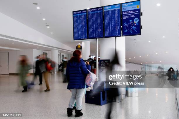 Woman watches the flights screen at JFK Airport on December 23, 2022 in New York City. Winter weather continues to disrupt holiday travel across the...