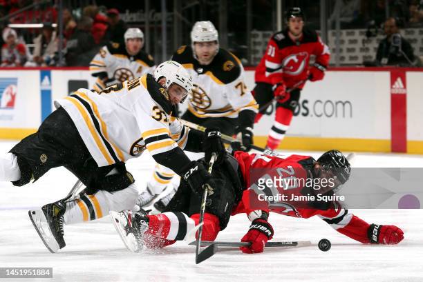 Michael McLeod of the New Jersey Devils is checked by Patrice Bergeron of the Boston Bruins during the 1st period of the game at Prudential Center on...