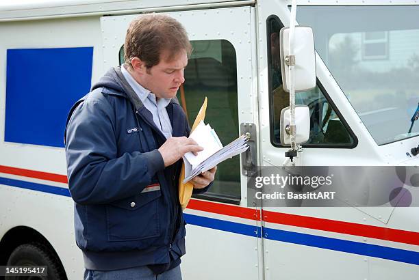 mail carrier sorting mail near delivery truck - postbode stockfoto's en -beelden