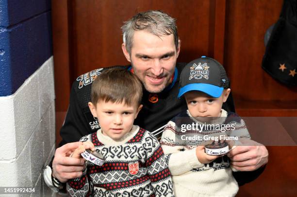 Alex Ovechkin of the Washington Capitals and his sons Sergei and Ilya hold the pucks for goals and after the game against the Winnipeg Jets at...