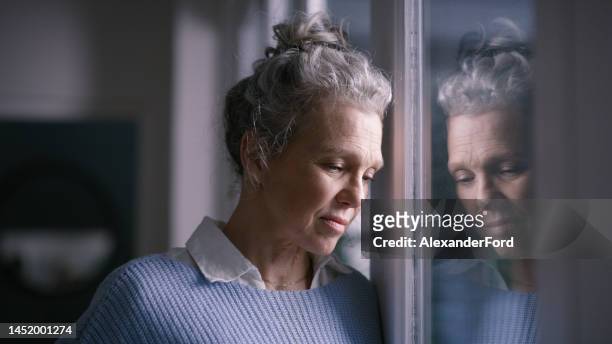 depression, sad and senior woman by window looking, upset, lonely and unhappy in retirement home. mental health, loneliness and and depressed elderly female thinking of problem, issues and crisis - smärta bildbanksfoton och bilder