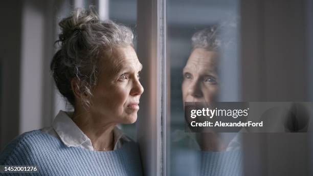 depression, lonely and thinking senior woman in a nursing home with mental health problem, idea and sad with a window reflection. anxiety, stress and elderly person with fear, depressed and dementia - dementie stockfoto's en -beelden