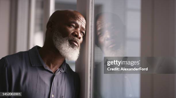 triste, depressão ou homem negro esgotado na janela com saúde mental, dor de cabeça ou ansiedade em casa. homem solitário, estressado ou deprimido pensando em problemas financeiros, conformidade com a saúde ou política financeira - loss - fotografias e filmes do acervo