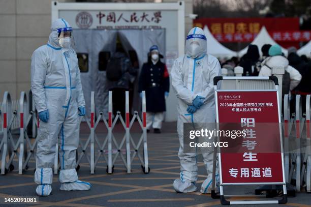 Workers wearing personal protective equipment stand at a special access, which is set up for examinees who have a positive nucleic acid test result,...