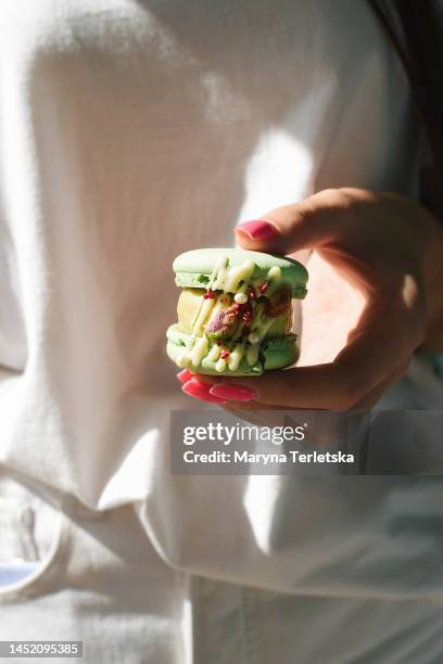 delicious macaroon dessert bitten in hands. sweet food. confectionery. - biskvi bildbanksfoton och bilder