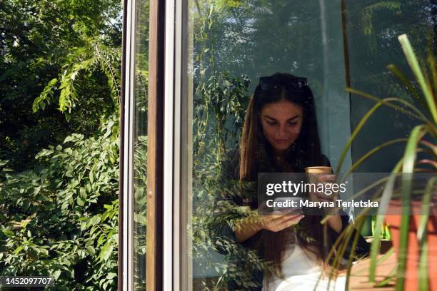 a girl sits at a table in a cafe. a woman is having breakfast in a cafe. the woman looks at her phone and scrolls through the feed. social network. dating site. selfie. photo. - selbstverliebt stock-fotos und bilder