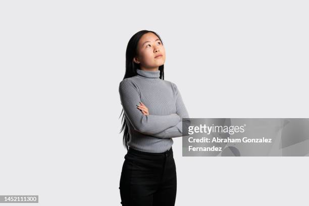 asian woman looking up with a doubtful expression - suspicion employee stock pictures, royalty-free photos & images