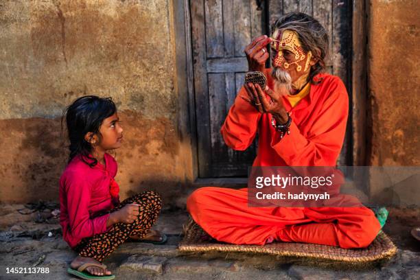 niña observando cómo sadhu se maquilla - valle de kathmandu fotografías e imágenes de stock