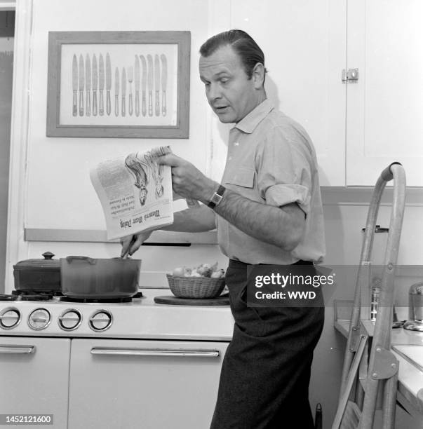Designer Bill Blass photographed at home reading Women's Wear Daily.