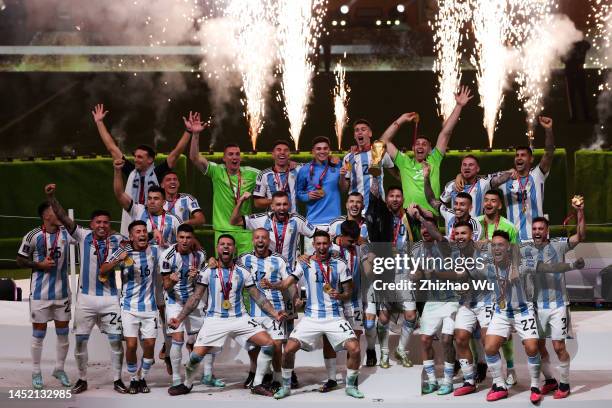 Lionel Messi of Argentina rise up The FIFA World Cup Qatar 2022 Winner's Trophy and celebrates the champion with teammates during the award ceremony...