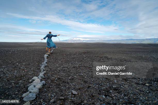 girl with a dress and barefoot balancing on some stones on the beaches of iceland, girl with a dress enjoying the endless beaches of iceland, dresses in landscapes - アイスランド文化 ストックフォトと画像