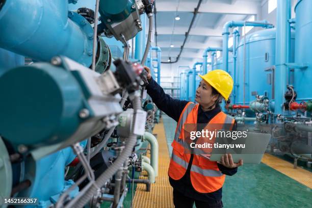 a female engineer works in a chemical plant using a laptop computer - oil industry stock pictures, royalty-free photos & images