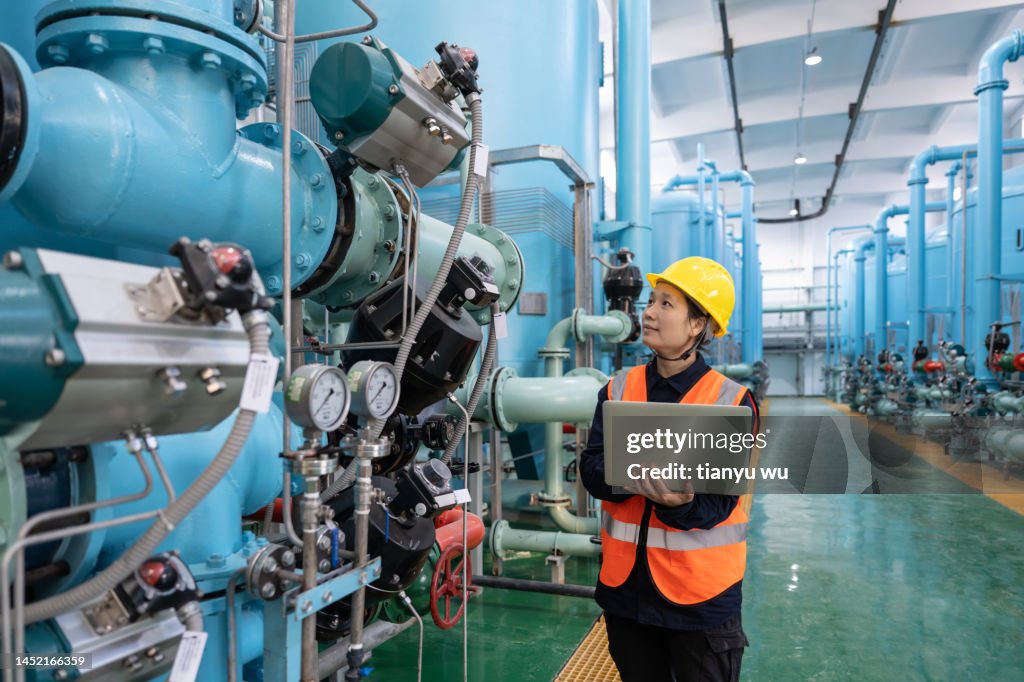 A female engineer works in a chemical plant using a laptop computer