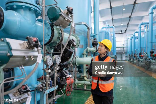 a female engineer works in a chemical plant using a laptop computer - gas engineer stockfoto's en -beelden