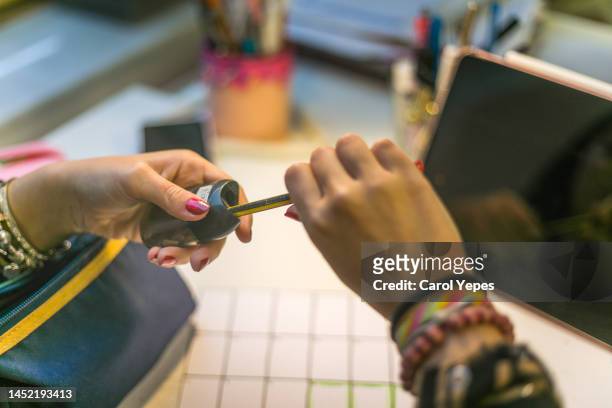 female sharpening pencil at desk - pencil sharpener stockfoto's en -beelden