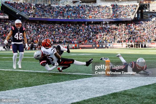 Tee Higgins of the Cincinnati Bengals runs over Jonathan Jones of the New England Patriots while scoring a receiving touchdown during the first...