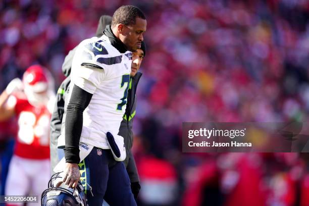 Geno Smith of the Seattle Seahawks walks off the field with medical staff during the second quarter against the Kansas City Chiefs at Arrowhead...