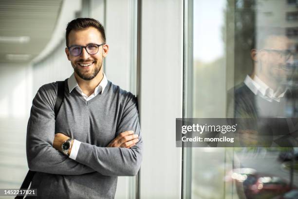 junger geschäftsmann steht in einem flur eines modernen innengebäudes neben dem fenster - economist stock-fotos und bilder