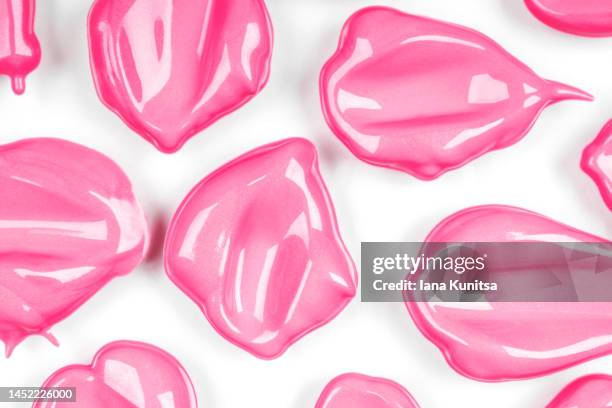 pink lipstick smears on white background, isolated. lip gloss samples are smudged. beauty cosmetic pattern. makeup and skin care products. - lip gloss smudge stock-fotos und bilder