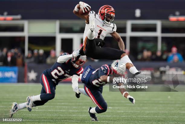 Myles Bryant of the New England Patriots and Marcus Jones of the New England Patriots tackle Ja'Marr Chase of the Cincinnati Bengals during the...
