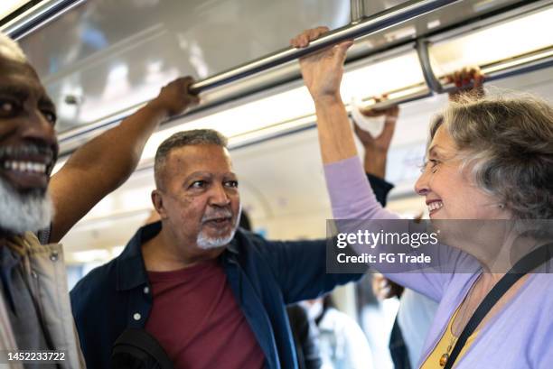 seniorenfreunde im gespräch in der u-bahn - lightrail stock-fotos und bilder