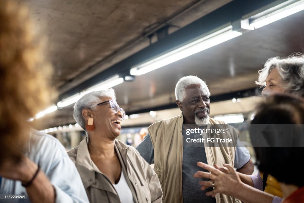 Amigos mais velhos conversando em um metrô