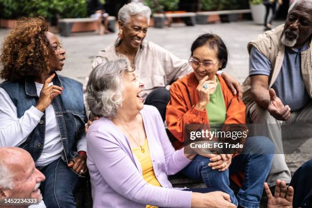 senior friends talking outdoors - seniors having fun ethnic diversity stock pictures, royalty-free photos & images