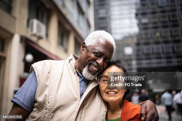 portrait of senior friends embracing outdoors - street style couple stock pictures, royalty-free photos & images