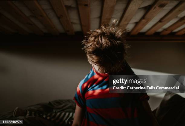 a child inserts his head through the neck hole of his t-shirt. his hair is messy as he pops it through the top. - visage caché par les cheveux photos et images de collection