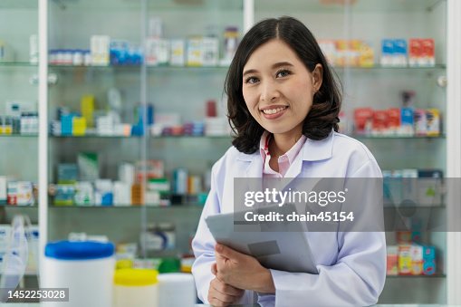 Asian Pharmacist with tablet for checking stock in local Pharmacy drug store in small business. Small local business of pharmacy drug store in the local area with digital transformation.