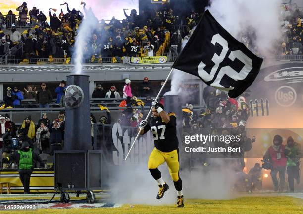 Cameron Heyward of the Pittsburgh Steelers runs on to the field holding a flag to honor Franco Harris during the game against the Las Vegas Raiders...