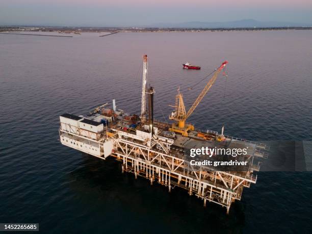 drohne schoss massive offshore-bohranlage mit long beach und los angeles kalifornien im hintergrund in der abenddämmerung - ölpest stock-fotos und bilder