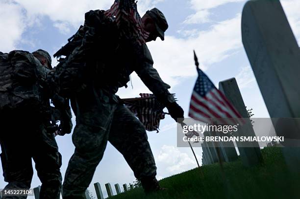 Soldier plants a flag at a grave in Arlington National Cemetery May 24, 2012 in Washington, DC. American service members and others participated in...