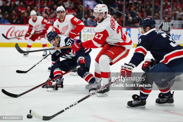 Michael Rasmussen of the Detroit Red Wings battles Trevor van Riemsdyk and Nick Jensen of the Washington Capitals for the puck during the first...