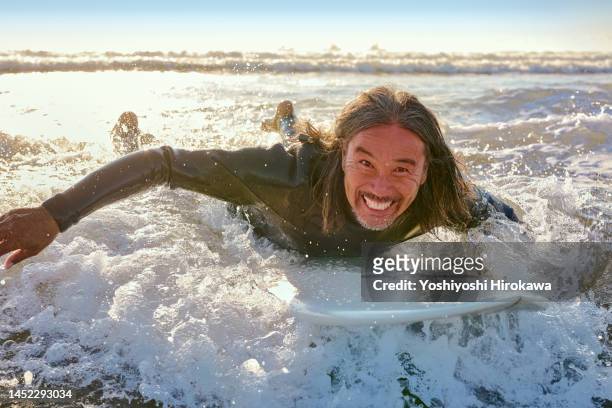 mature father rides the wave in the early morning light - asian surfer stockfoto's en -beelden