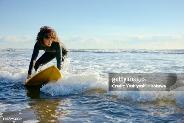 mature young mother rides early morning wave - surfing stock pictures, royalty-free photos & images