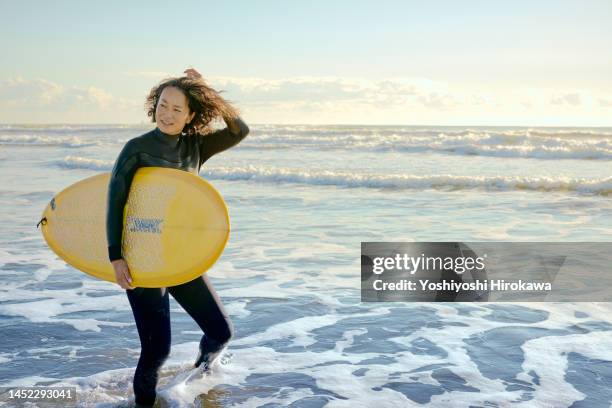 mature young mother rides early morning wave - ankle deep in water stock pictures, royalty-free photos & images