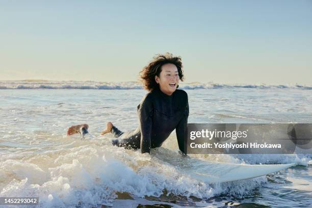 mature young mother rides early morning wave - asian woman smiling sunrise stock pictures, royalty-free photos & images