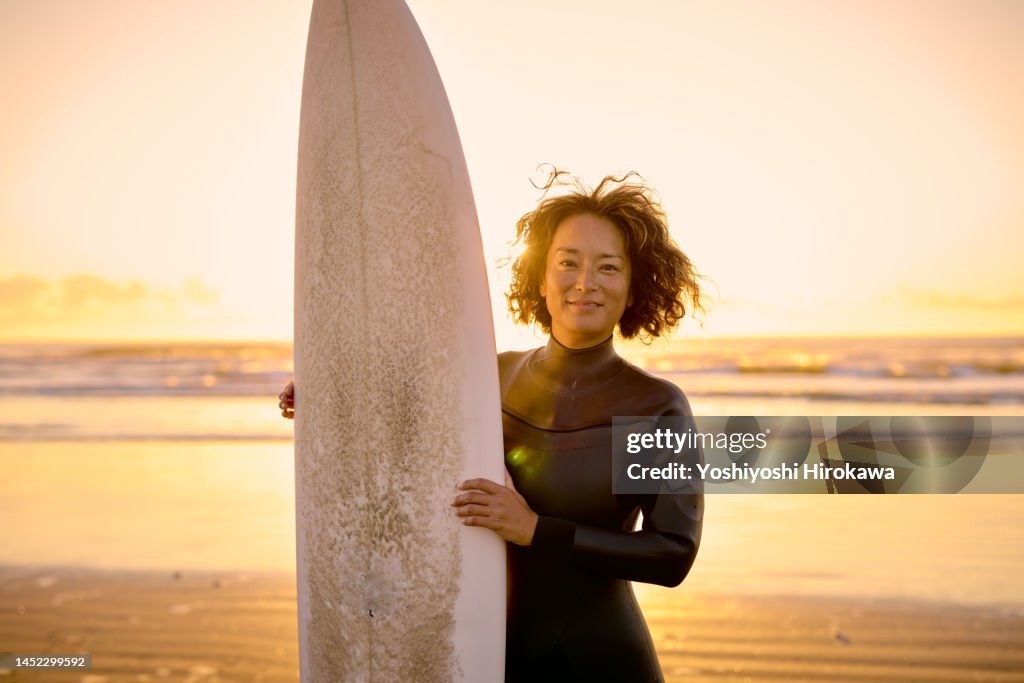 Portrait of mother standing on beach against morning sun