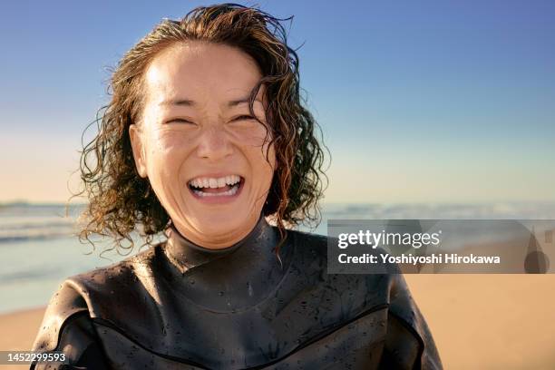 portrait of laughing mother standing on beach next to morning sun - older woman wet hair stock pictures, royalty-free photos & images